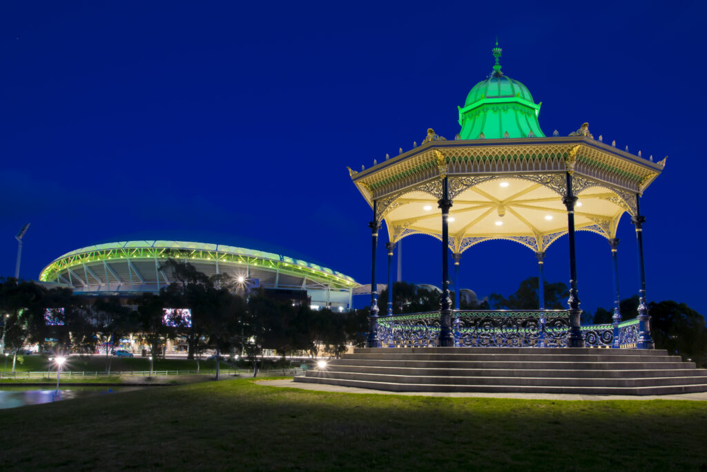 Elder Park Rotunda in Adelaide at night with a view of Adelaide Oval in the background.